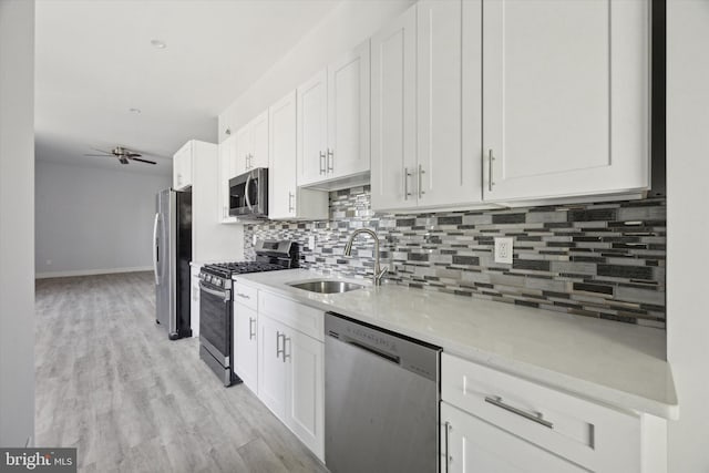 kitchen with sink, light hardwood / wood-style flooring, ceiling fan, white cabinetry, and stainless steel appliances