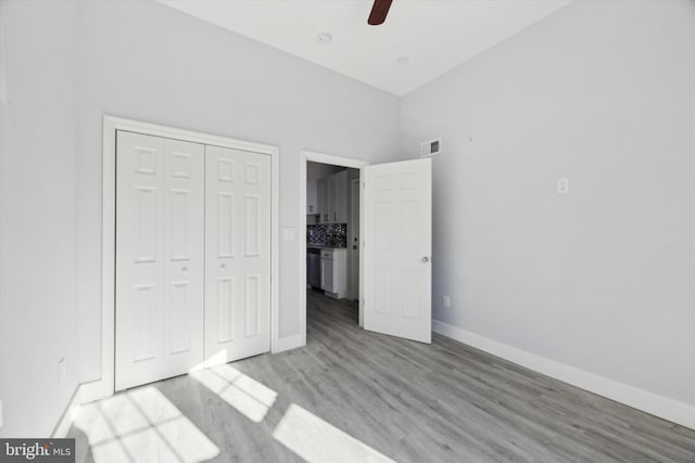 unfurnished bedroom featuring a towering ceiling, light hardwood / wood-style floors, a closet, and ceiling fan