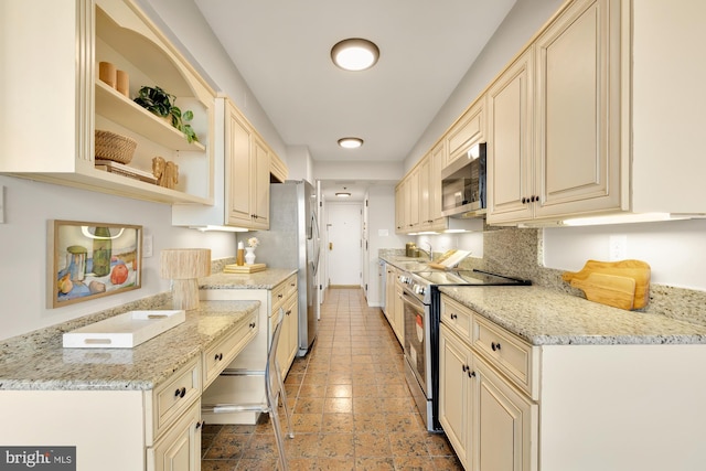 kitchen featuring stainless steel appliances, cream cabinets, and light stone countertops