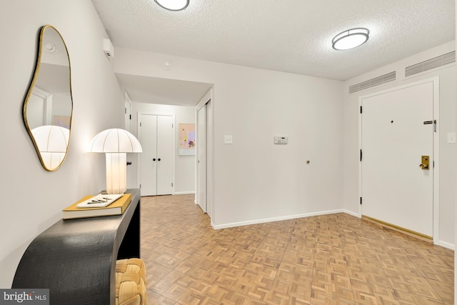 foyer entrance featuring a textured ceiling and light parquet flooring