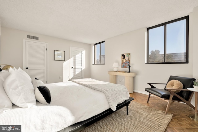 bedroom featuring a textured ceiling, a closet, parquet floors, and multiple windows