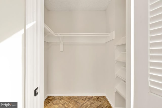 walk in closet featuring parquet flooring