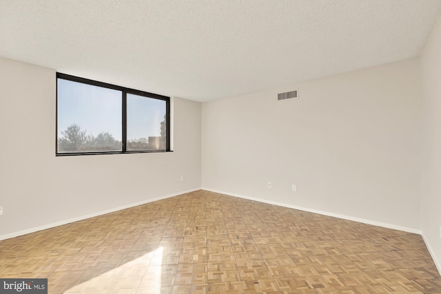 empty room with a textured ceiling and light parquet floors