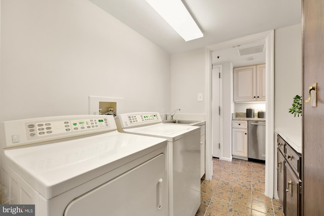 laundry area with washing machine and dryer, cabinets, and sink