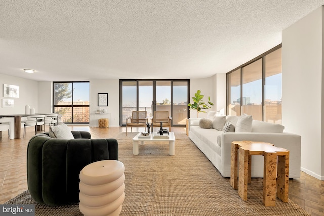 living room featuring a textured ceiling, a wall of windows, and plenty of natural light