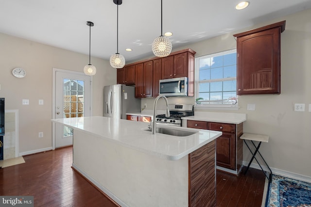 kitchen with a wealth of natural light, decorative light fixtures, a kitchen island with sink, and appliances with stainless steel finishes