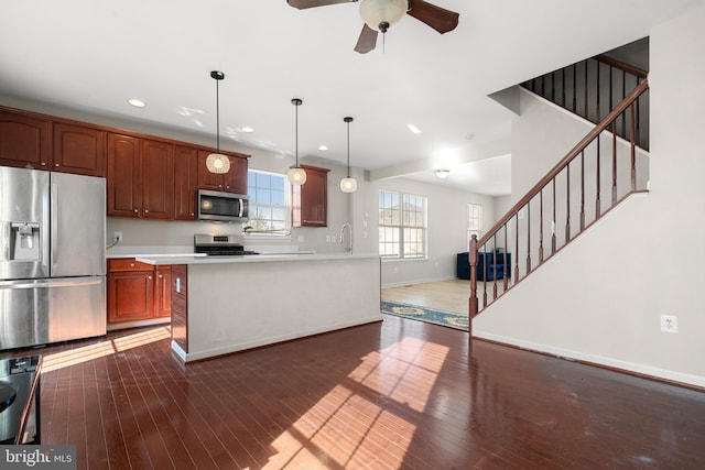 kitchen with appliances with stainless steel finishes, ceiling fan, dark wood-type flooring, sink, and pendant lighting