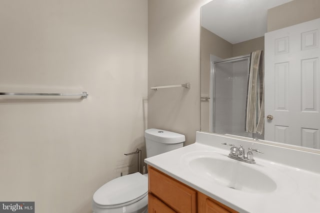 bathroom featuring vanity, a shower with shower door, and toilet