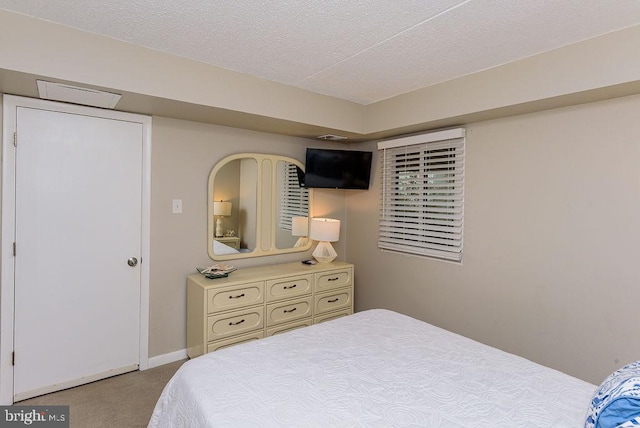 bedroom with light colored carpet and a textured ceiling