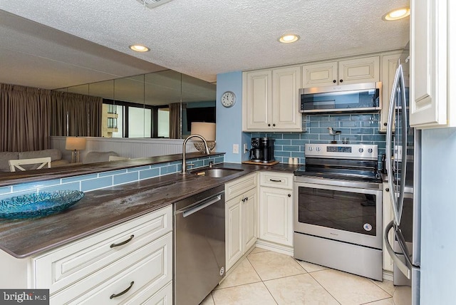 kitchen featuring sink, light tile patterned floors, tasteful backsplash, kitchen peninsula, and stainless steel appliances