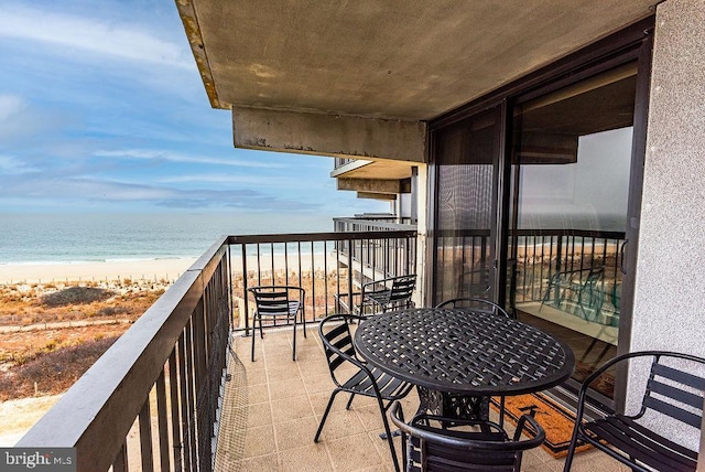 balcony with a water view and a view of the beach