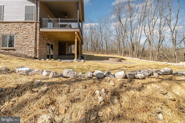 107 S Honeysuckle Dr, Hazle Township, PA 18202 - view of side of home featuring a balcony, stone siding, and a lawn