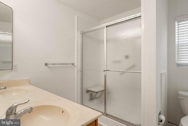 bathroom with vanity, a textured ceiling, toilet, and walk in shower