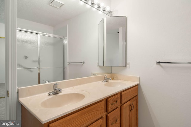 bathroom with vanity, a textured ceiling, and walk in shower