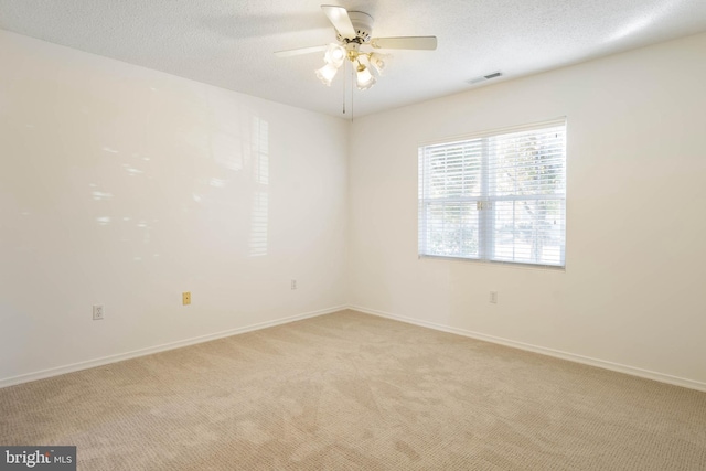 unfurnished room with ceiling fan, light colored carpet, and a textured ceiling