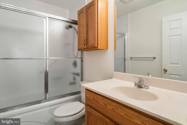 full bathroom featuring shower / bath combination with glass door, vanity, a textured ceiling, and toilet