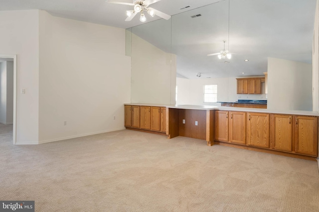 kitchen with ceiling fan, light colored carpet, kitchen peninsula, and high vaulted ceiling