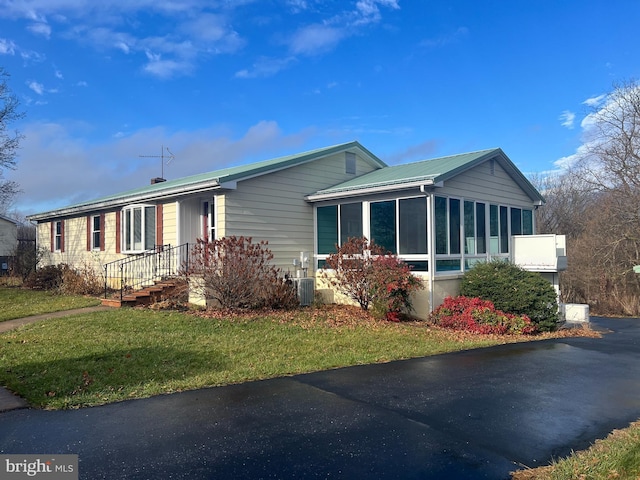 view of front of home featuring a sunroom and a front yard