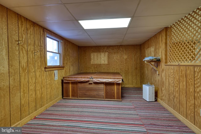 misc room with light carpet, a paneled ceiling, and wood walls