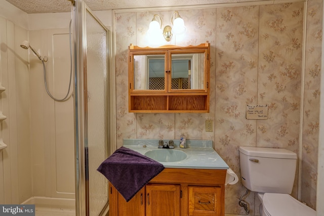 bathroom featuring vanity, toilet, a shower with shower door, and a textured ceiling