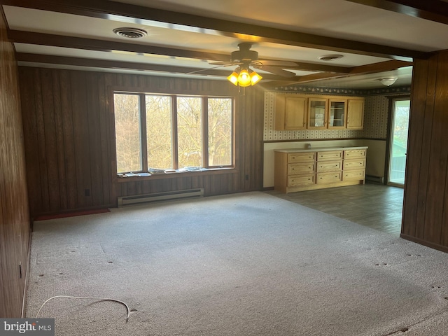 unfurnished living room featuring beam ceiling, wooden walls, dark carpet, and a baseboard heating unit