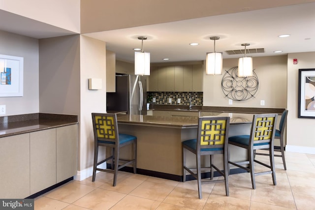 kitchen featuring tasteful backsplash, stainless steel fridge, sink, and hanging light fixtures