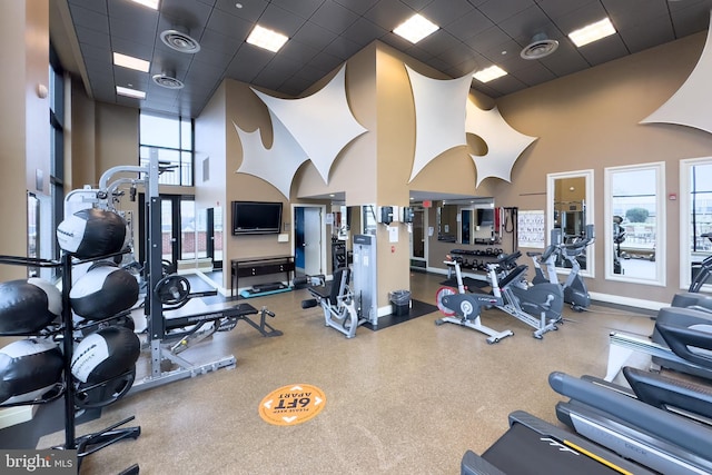 workout area featuring a drop ceiling and a towering ceiling