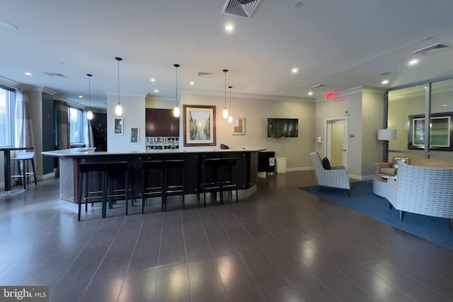 kitchen featuring hanging light fixtures, dark hardwood / wood-style floors, a spacious island, a breakfast bar area, and ornamental molding