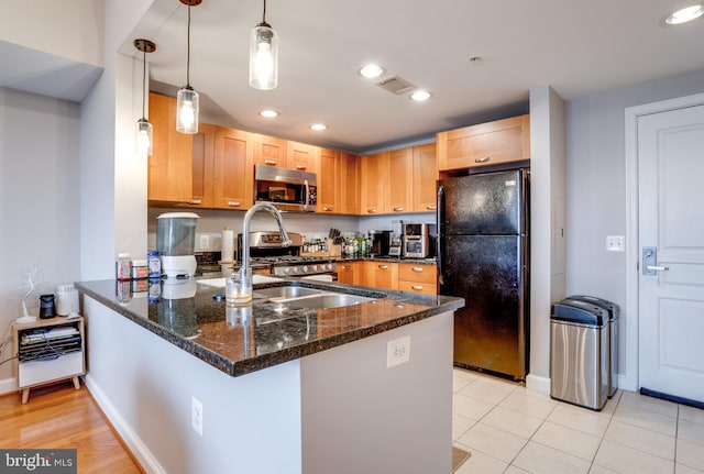 kitchen with pendant lighting, kitchen peninsula, appliances with stainless steel finishes, and dark stone counters