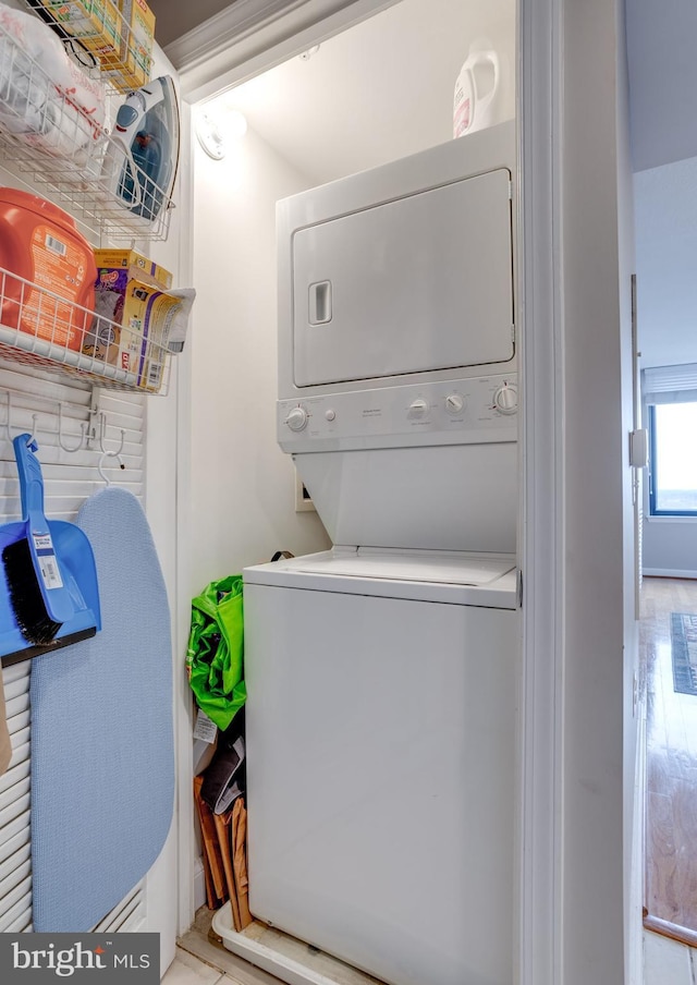 clothes washing area with stacked washer and dryer and light hardwood / wood-style flooring