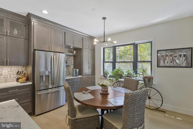 dining area with light wood-type flooring and an inviting chandelier