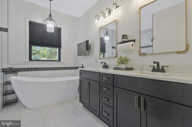 bathroom with tile patterned flooring, a bath, a chandelier, vanity, and tile walls