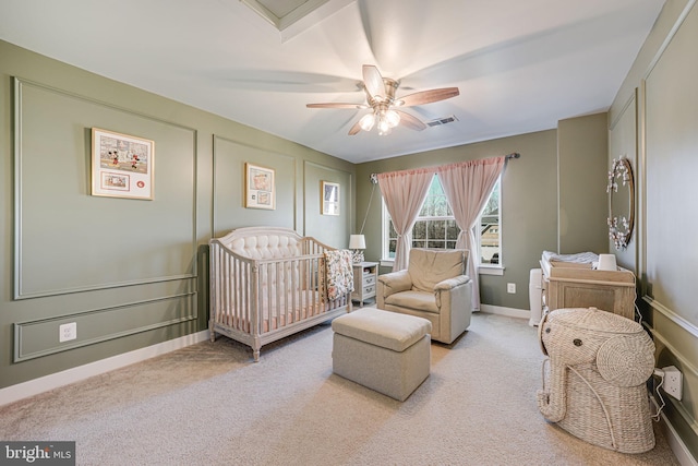 bedroom featuring ceiling fan, light colored carpet, and a nursery area