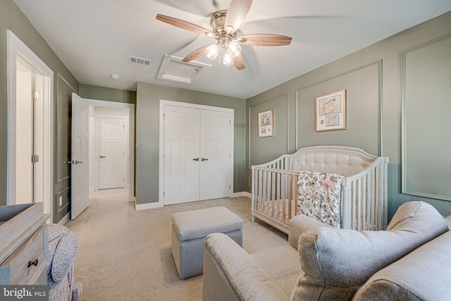 carpeted bedroom with ceiling fan, a closet, and a crib