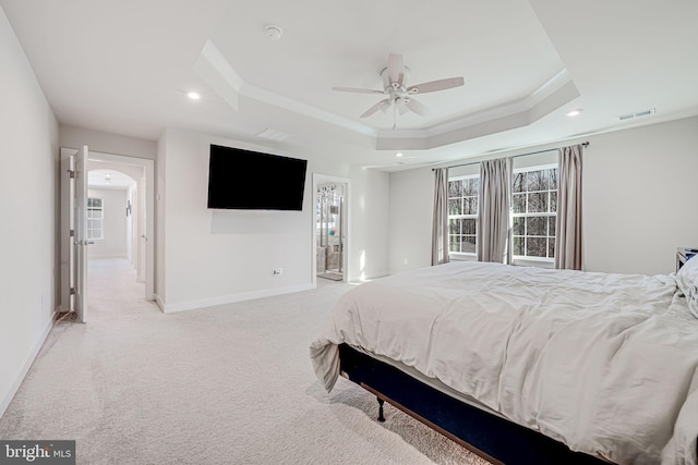 carpeted bedroom with a tray ceiling, ceiling fan, and ornamental molding