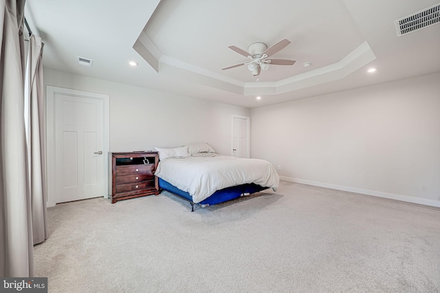 carpeted bedroom with ceiling fan, stainless steel refrigerator, and a tray ceiling