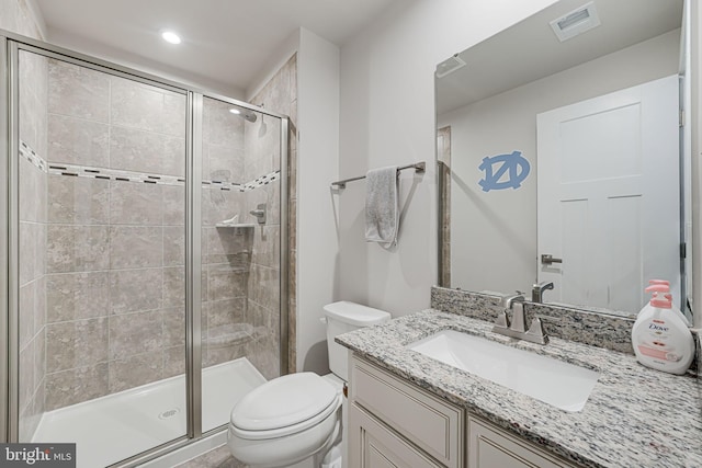 bathroom with a shower with door, vanity, and toilet