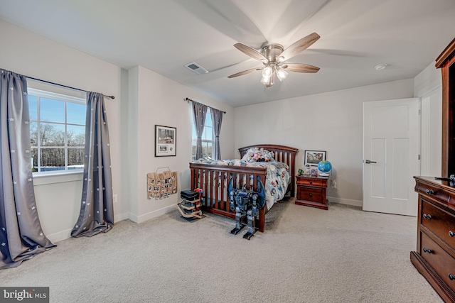 bedroom with ceiling fan, light colored carpet, and multiple windows