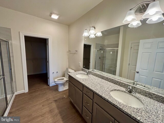 bathroom featuring vanity, toilet, wood-type flooring, and a shower with door