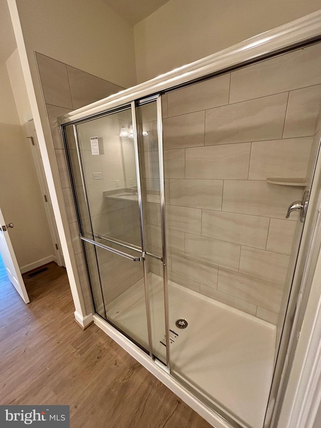 bathroom featuring an enclosed shower and wood-type flooring