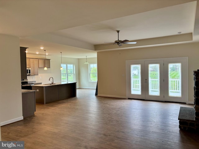 unfurnished living room with dark hardwood / wood-style flooring, ceiling fan, and sink