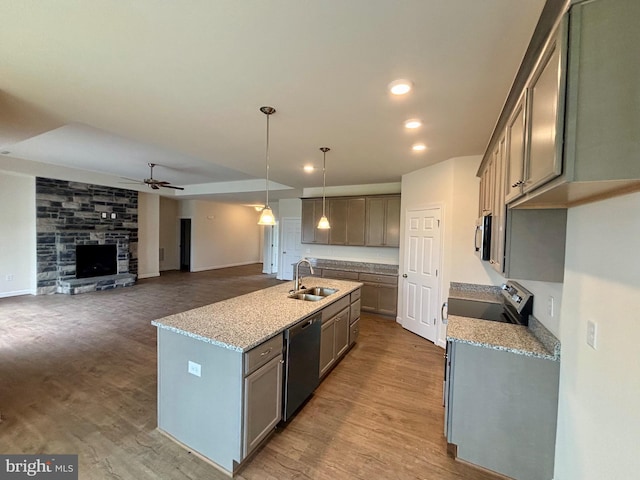 kitchen with light stone countertops, sink, decorative light fixtures, appliances with stainless steel finishes, and hardwood / wood-style flooring