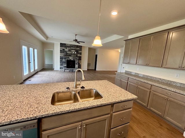 kitchen featuring light stone countertops, sink, pendant lighting, dishwasher, and hardwood / wood-style floors