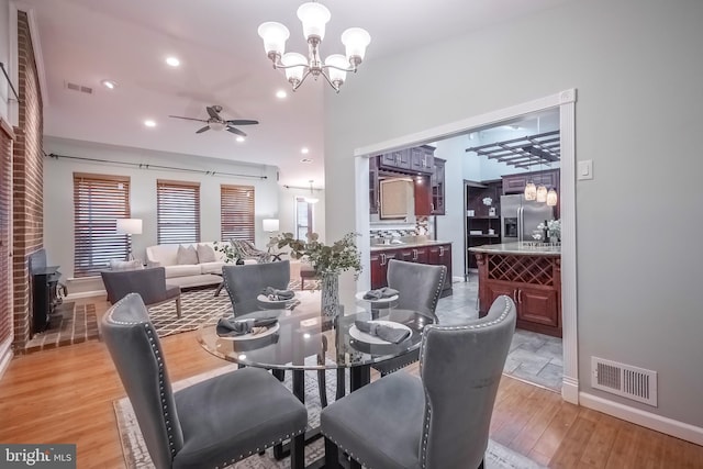 dining area featuring light wood-type flooring and ceiling fan with notable chandelier