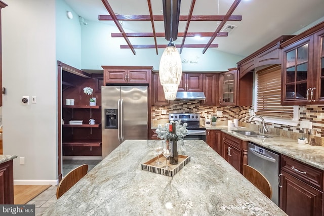 kitchen with lofted ceiling with beams, sink, tasteful backsplash, decorative light fixtures, and stainless steel appliances