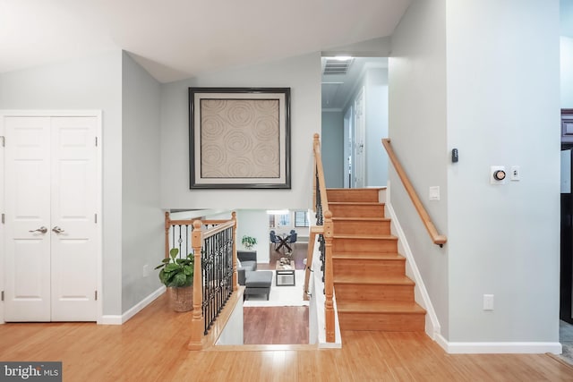 staircase with vaulted ceiling and hardwood / wood-style flooring