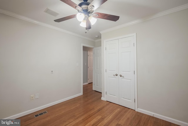 unfurnished bedroom featuring hardwood / wood-style floors, ceiling fan, ornamental molding, and a closet