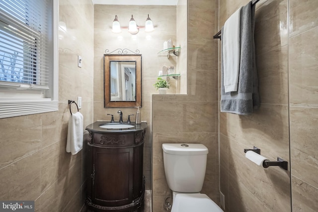 bathroom with vanity, toilet, and tile walls