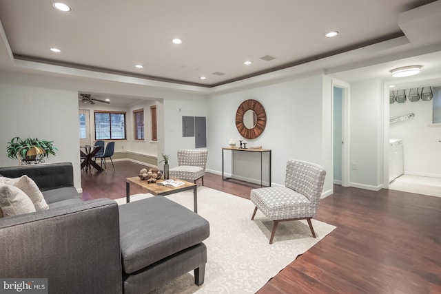 living room with dark hardwood / wood-style floors, ceiling fan, and a raised ceiling