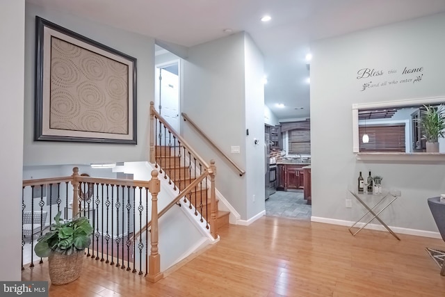 stairway with hardwood / wood-style floors and sink